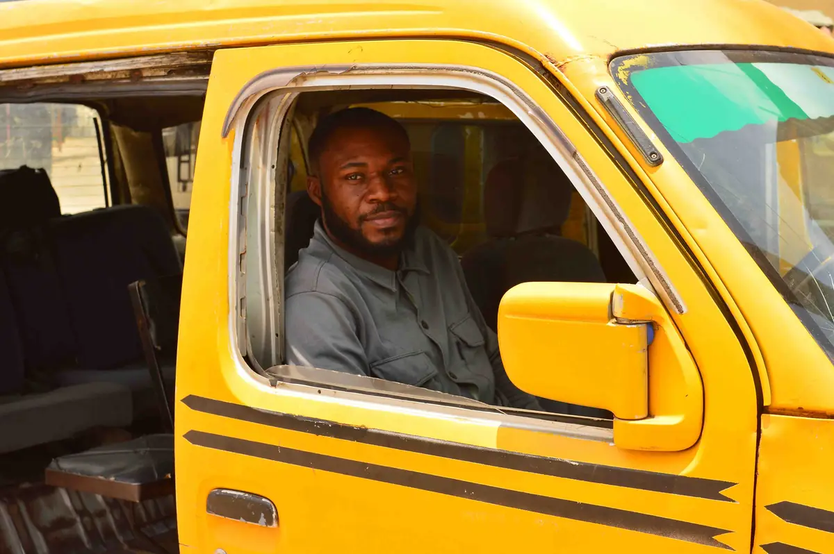A bus driver looks out from the window of his yellow bus.